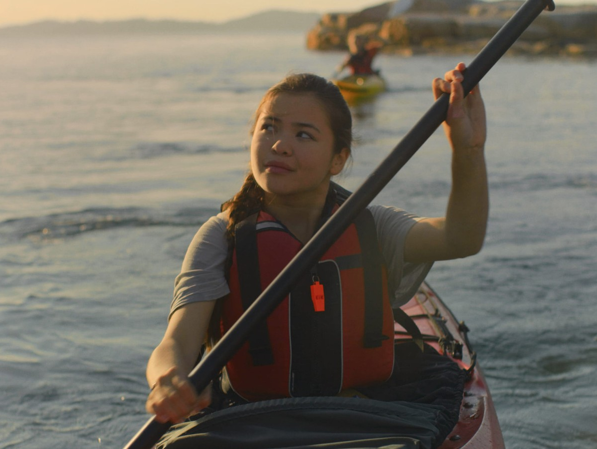 a woman rows a canoe in the setting sun