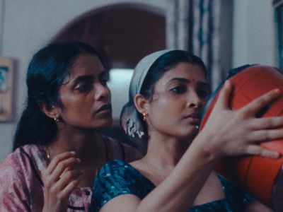 Two women framed in close-up look into an orange bucket in a still from All We Imagine As Light