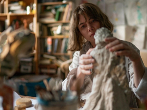 A woman works on a clay sculpture in a studio in a still from Kelly Reichardt's Showing Up.